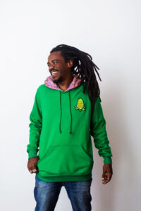 Moletom verde da CrocBuds em modelo sorridente com calça jeans e rastas