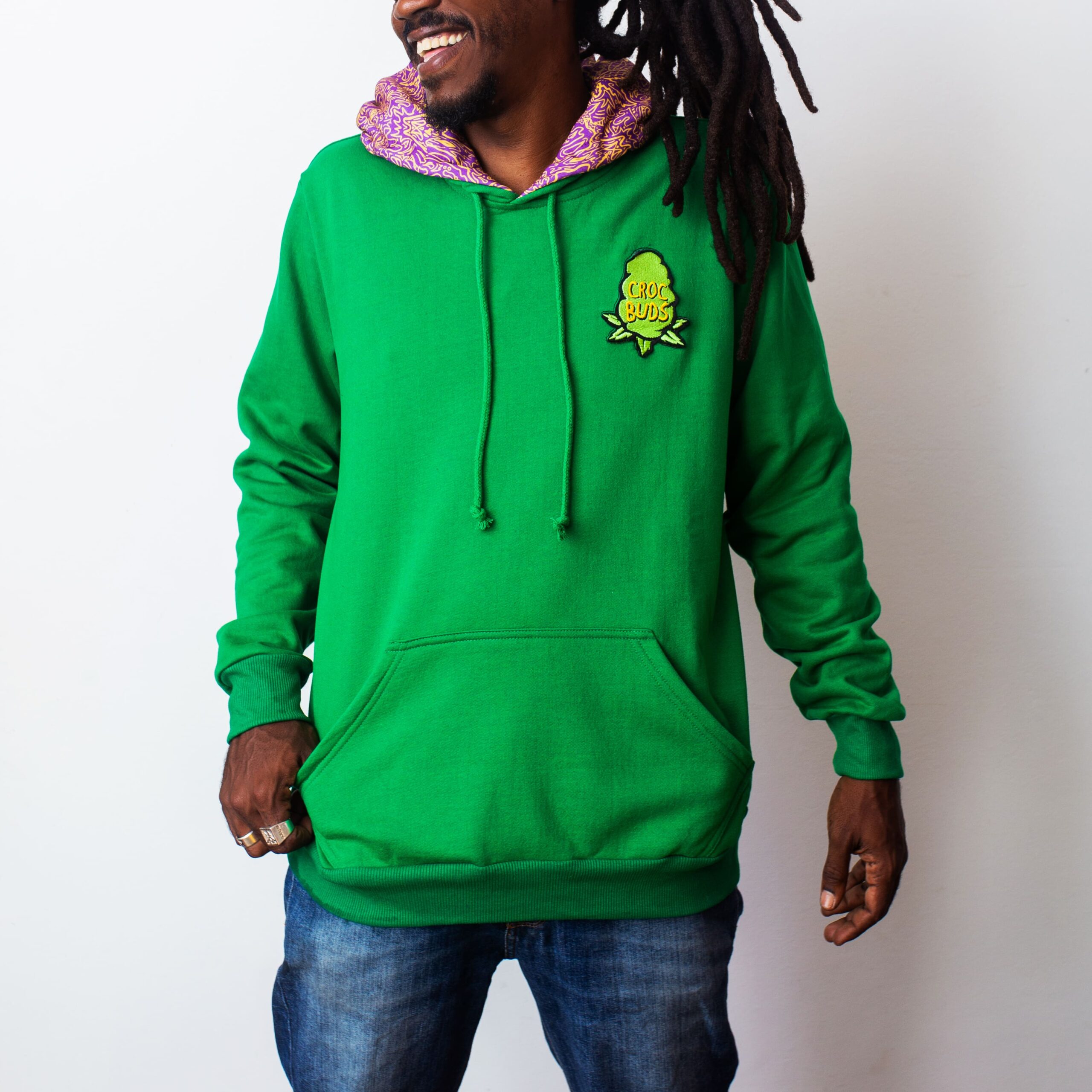 Moletom verde da CrocBuds em modelo sorridente com calça jeans e rastas